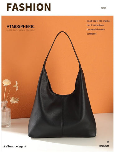 Black retro large-capacity tote bag with a single shoulder strap on an orange backdrop.